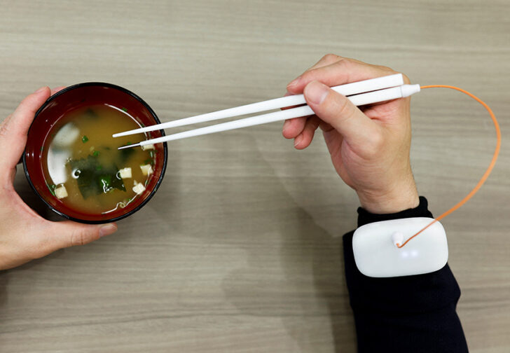 An employee of Kirin Holdings demonstrates chopsticks that can enchance food taste using an electrical stimulation waveform in Tokyo ตะเกียบไฟฟ้า