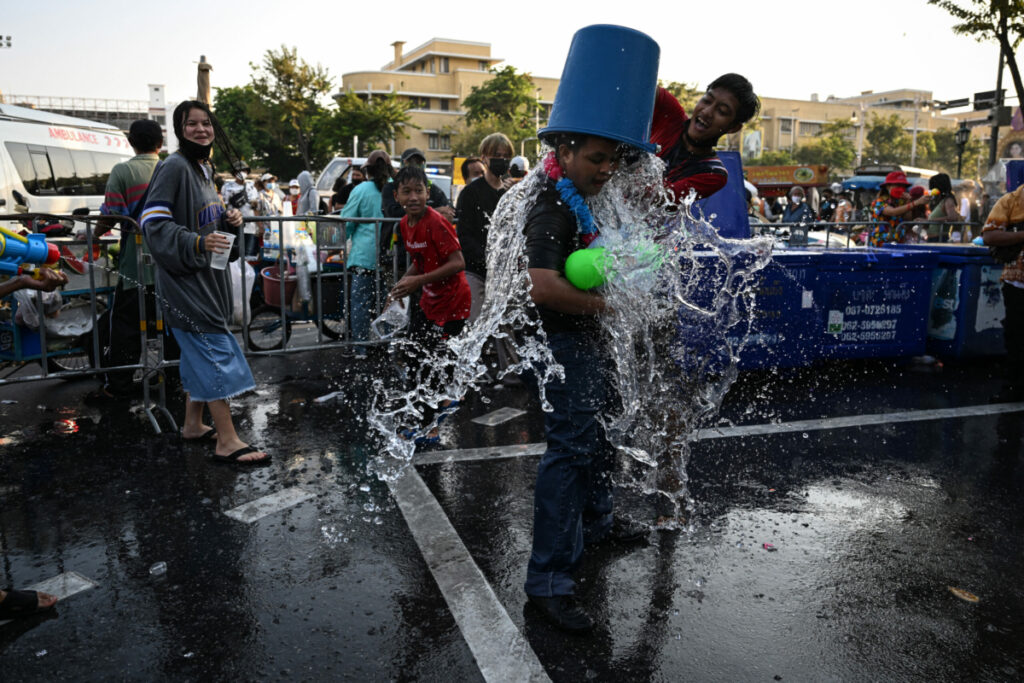 นักท่องเที่ยวคว่ำถังน้ำ บนศีรษะผู้เข้าร่วมงานเทศกาลสงกรานต์อีกราย ใบหน้าผู้คนโดยรอบปรากฏรอยยิ้ม