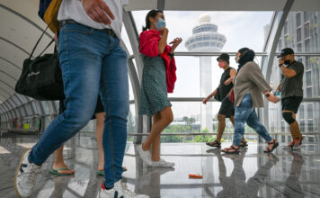 ผู้คนเดินผ่านสะพานเชื่อมระหว่างอาคารผู้โดยสารในสนามบินชางงี ประเทศสิงคโปร์
