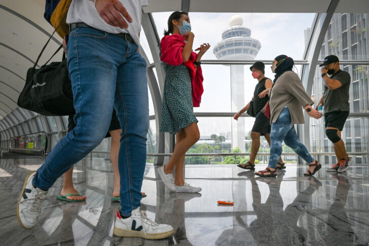 ผู้คนเดินผ่านสะพานเชื่อมระหว่างอาคารผู้โดยสารในสนามบินชางงี ประเทศสิงคโปร์