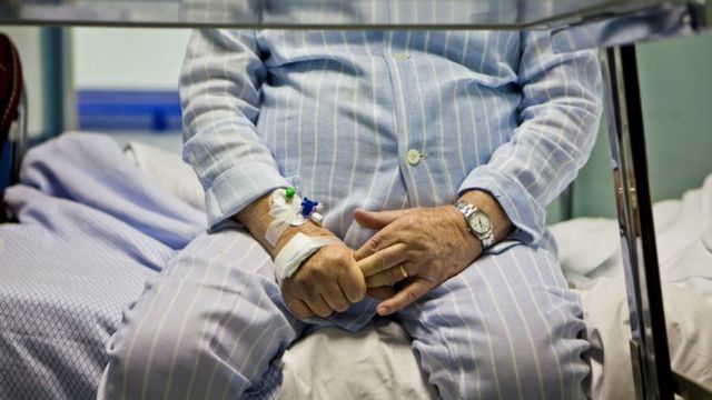 An elderly man sitting on a hospital bed