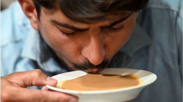 A man drinks tea from a saucer at a restaurant in Islamabad