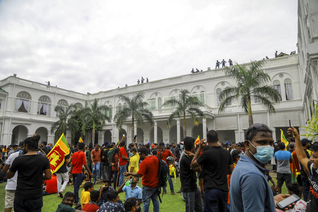 Protesters react as a tear gas shell fired by police lands next to them in Colombo, Sri Lanka, Saturday, July 9, 2022. Sri Lankan protesters demanding that President Gotabaya Rajapaksa resign forced their way into his official residence on Saturday, a local television report said, as thousands of people took to the streets in the capital decrying the island nation's worst economic crisis in recent memory.