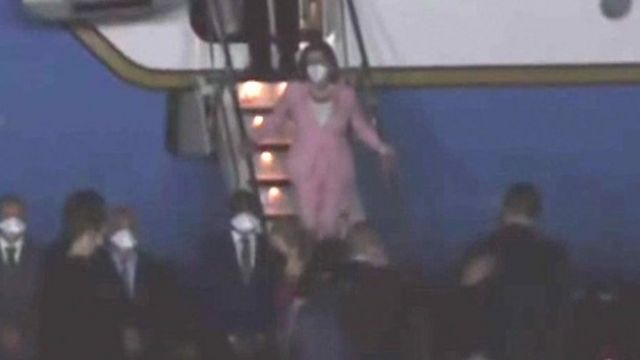 Nancy Pelosi in pink suit walking down stairs off aeroplane