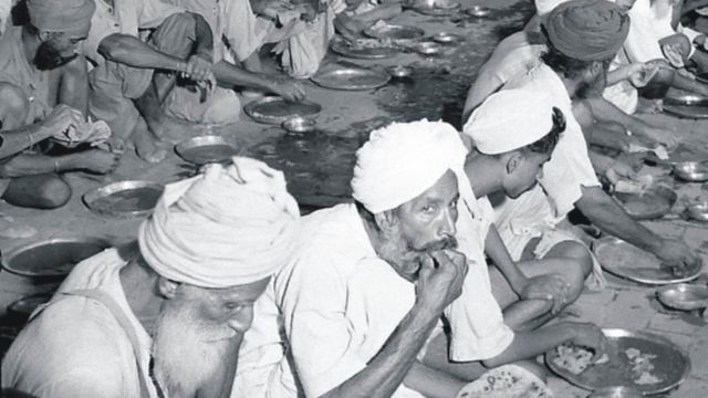 Sikh refugees eating free food on the ground in a relief camp in Amritsar in 1947/1948.