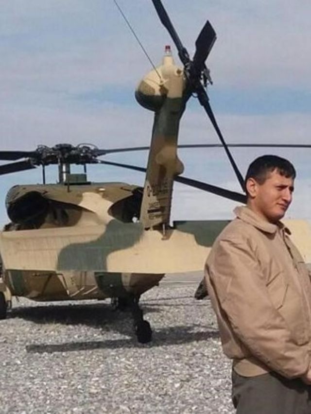 Momand standing n front of his helicopter