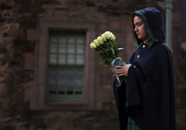 A Warden of the Palace of Holyroodhouse holds flowers