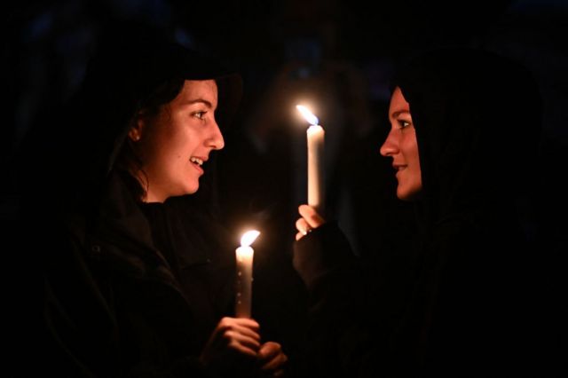 People hold candles outside Buckingham Palace