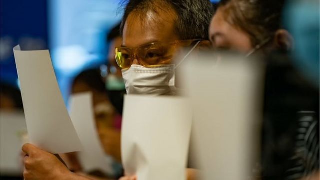Pro-democracy protesters in Hong Kong waving blank signs in 2020