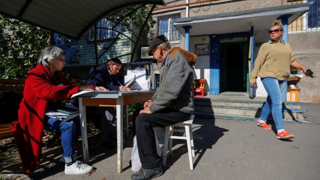 A woman registers a man for voting in the discredited referendum outside an apartment block in Mariupol