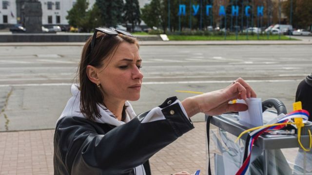 A woman casts her ballot at an outdoor polling booth in a Luhansk street