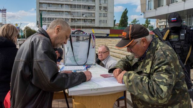 People fill in ballot paper in front of each other at an outdoor polling station in Luhansk, eastern Ukraine.