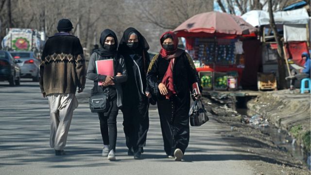 Students walk along a street near the Kabul University after it was reopened in Kabul on February 26, 2022. (Photo by Ahmad SAHEL ARMAN / AFP)