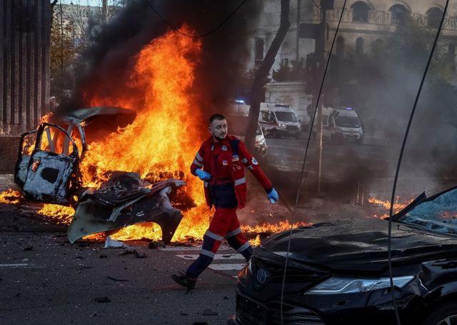 A medical worker walks near a burned car after Russian military strike, as Russia's invasion of Ukraine continues, in central Kyiv, Ukraine