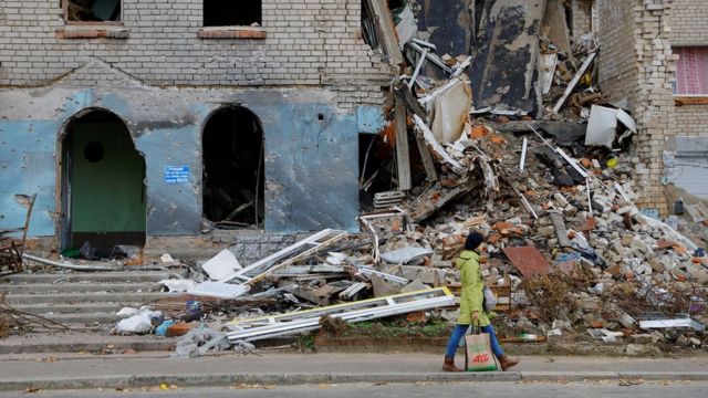 A woman walks past a building damaged in the course of Russia-Ukraine conflict in the town of Nova Kakhovka, Kherson region