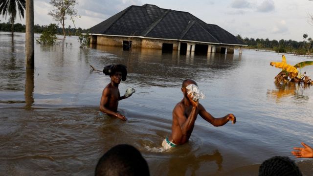Residents wade through flood water following a massive flood in Obagi Community, Rivers State, Nigeria.