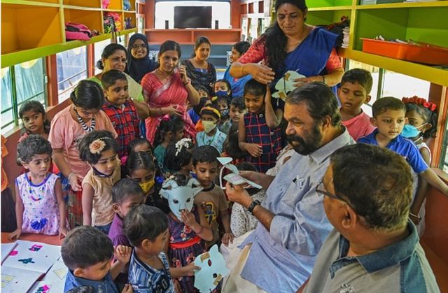 Kerala minister for general education V Sivankutty (2R) with students inside a re-modified low-floor old defunct public transport bus transformed into a classroom for pre-nursery school children through an initiative 'Education on Wheels' taken by the state government at Thiruvananthapuram on June 13, 2022