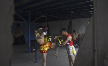 นักกีฬากำลังฝึกซ้อมมวยไทย โดยแทงเข่าไปยังเป้าล่อ ภาพถ่ายในศูนย์กีฬา ณ เมืองบามิยัน ประเทศอัฟกานิสถาน