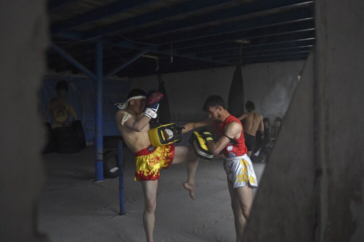 นักกีฬากำลังฝึกซ้อมมวยไทย โดยแทงเข่าไปยังเป้าล่อ ภาพถ่ายในศูนย์กีฬา ณ เมืองบามิยัน ประเทศอัฟกานิสถาน