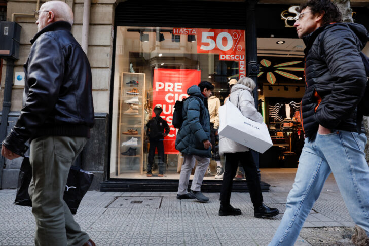 People walk past a clothing store advertising January sales in Bilbao IMF คาดการณ์เศรษฐกิจโลก