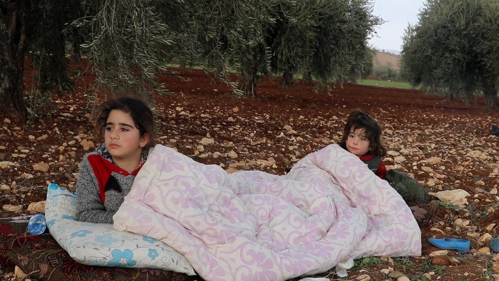 Two children sleeping on the side of the road with just blankets for warmth