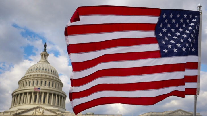 A flag is held aloft at the U.S. Capitol in Washington เศรษฐกิจสหรัฐ