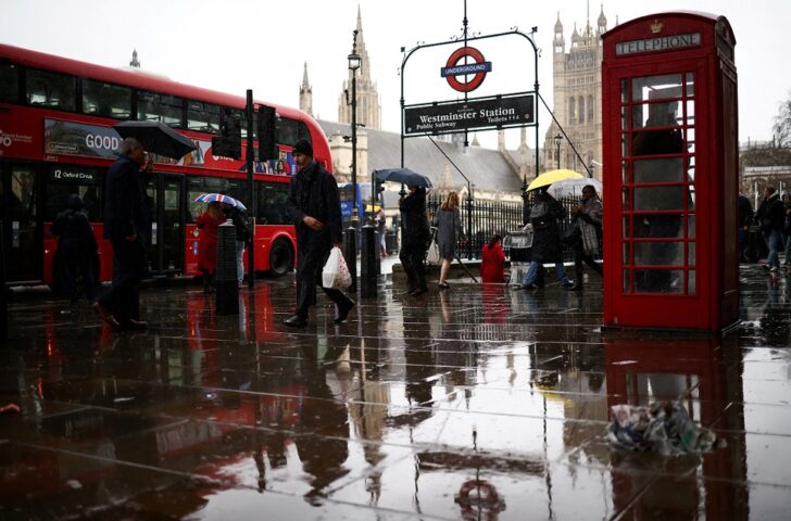 FILE PHOTO: People walk outside the Houses of Parliament during heavy rainfall in London อังกฤษ CPTPP
