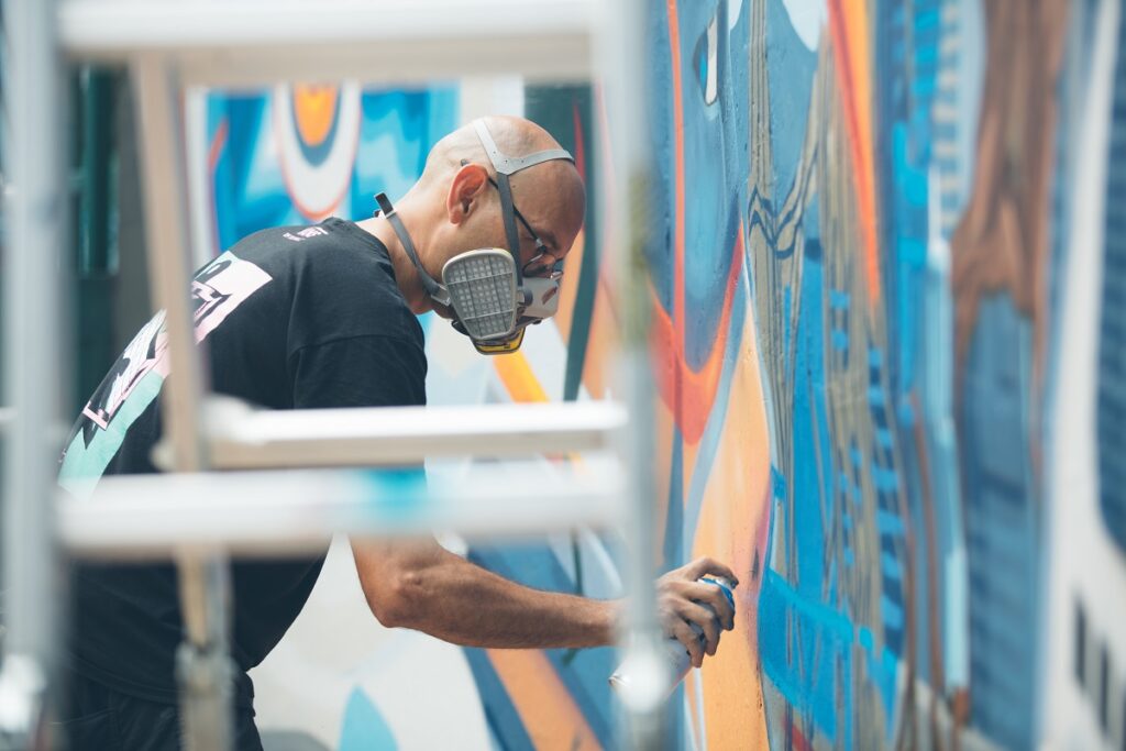 ศิลปินกำลังใช้สีเพนต์ลงบนกำแพง