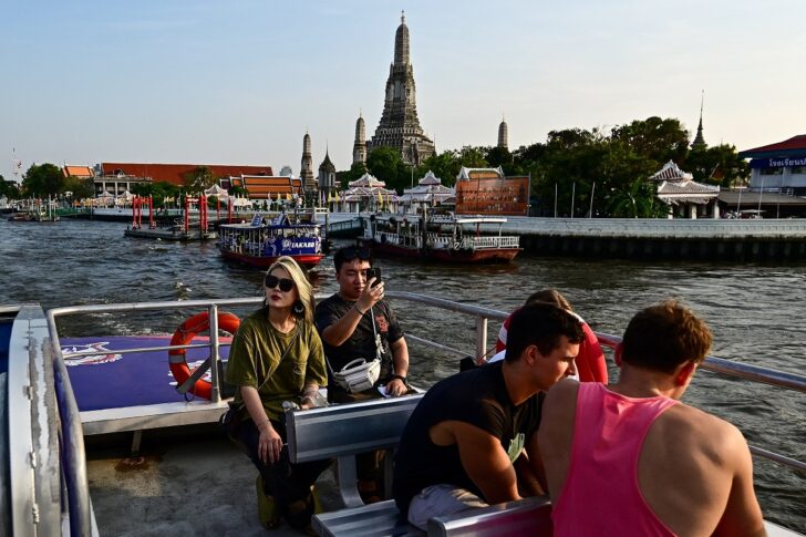 นักท่องเที่ยวนั่งเรือชมวิวสองฝั่งแม่น้ำเจ้าพระยา ด้านหลัง ปรากฏวิวพระปรางค์วัดอรุณราชวราราม