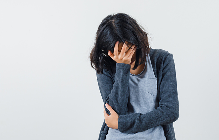 young girl covering face with hand in light gray t-shirt and da
