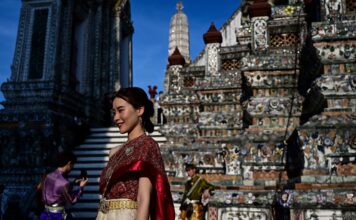 นักท่องเที่ยวไต้หวันสวมชุดไทย กำลังถ่ายภาพกับสถาปัตยกรรมของวัดอรุณราชวรารามราชวรมหาวิหาร