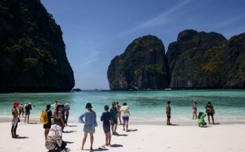 นักท่องเที่ยวถ่ายภาพอยู่บนชายหาดหน้าอ่าวมาหยา เกาะพีพีเล
