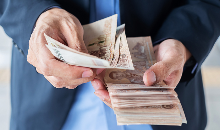 Businessman hand holding Thai Baht banknote stack. business, mon baht banknote