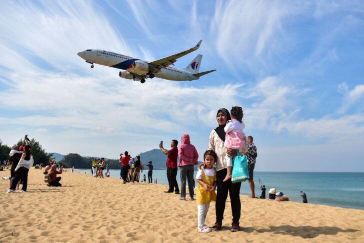 TOURISM-PHUKET-BEACH นักท่องเที่ยวยืนถ่ายภาพกับเครื่องบินขณะกำลังร่อนลงจอดสู่ท่าอากาศยานนานาชาติภูเก็ต บริเวณหาดไม้ขาว จังหวัดภูเก็ต