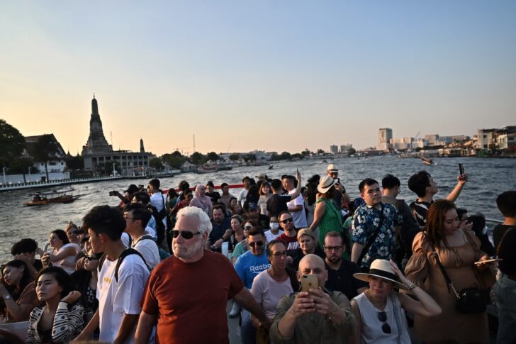 ชาวไทยและชาวต่างชาติ ล่องเรือท่องเที่ยวแม่น้ำเจ้าพระยา ชมทัศนียภาพโดยรอบ บางคนหยิบกล้องถ่ายรูปขึ้นมาถ่ายภาพ