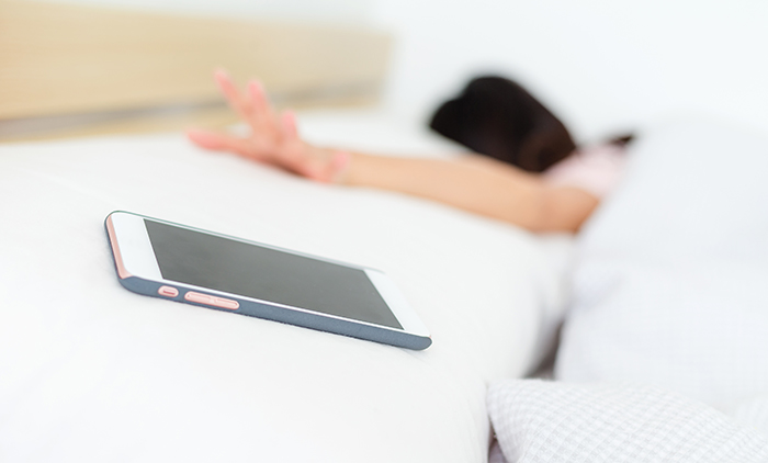 Woman waking up with mobile alarm clock