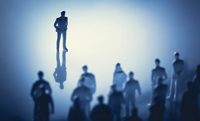 Single man standing in front of group of people.