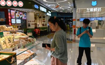ผู้หญิงกำลังจับจ่ายซื้อของที่ร้านค้าในห้างสรรพสินค้าแห่งหนึ่งในกรุงปักกิ่ง (ภาพโดย AFP)