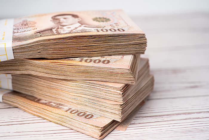 Stack of Thai baht banknotes on wooden background, business savi