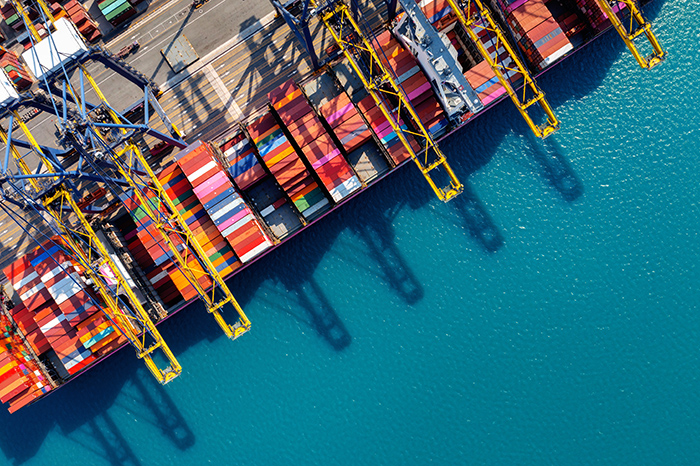 Aerial view of cargo ship and cargo container in harbor. โรงงานลดผลิต-ลุ้นภาษีทรัมป์ นับถอยหลัง 9 ก.ค.-ครึ่งหลังน่วม