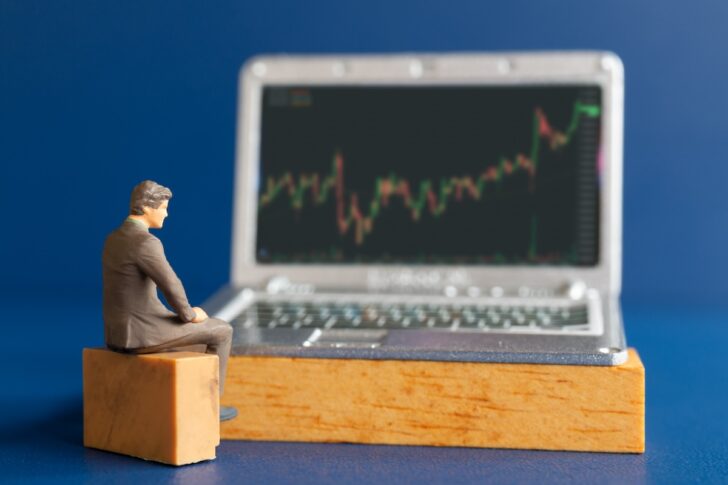 Miniature people, Business people and laptop featuring stock tickers Miniature people, Business people and laptop featuring stock tickers