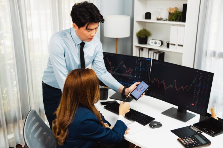 Smiling businessman showing stock market data on phone to woman. Infobahn.