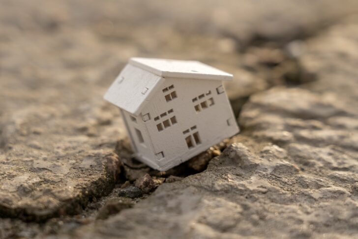 The house fell into a crack during an earthquake. Earthquake home insurance concept Real estate fall The house fell into a crack during an earthquake. Earthquake home insurance concept Real estate fall