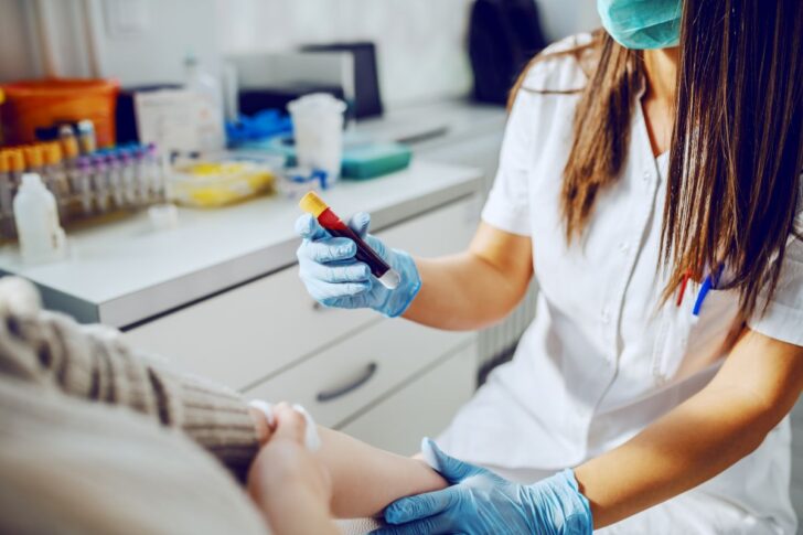 caucasian-laboratory-assistant-uniform-with-mask-rubber-gloves-holding-test-tube-with-blood-while-patient-sitting-holding-absorbent-cotton HIV ระบาดหนัก ปี 68 ติดเชื้อพุ่งทะลุครึ่งล้าน ป่วยรายใหม่กว่า 13,000 ราย