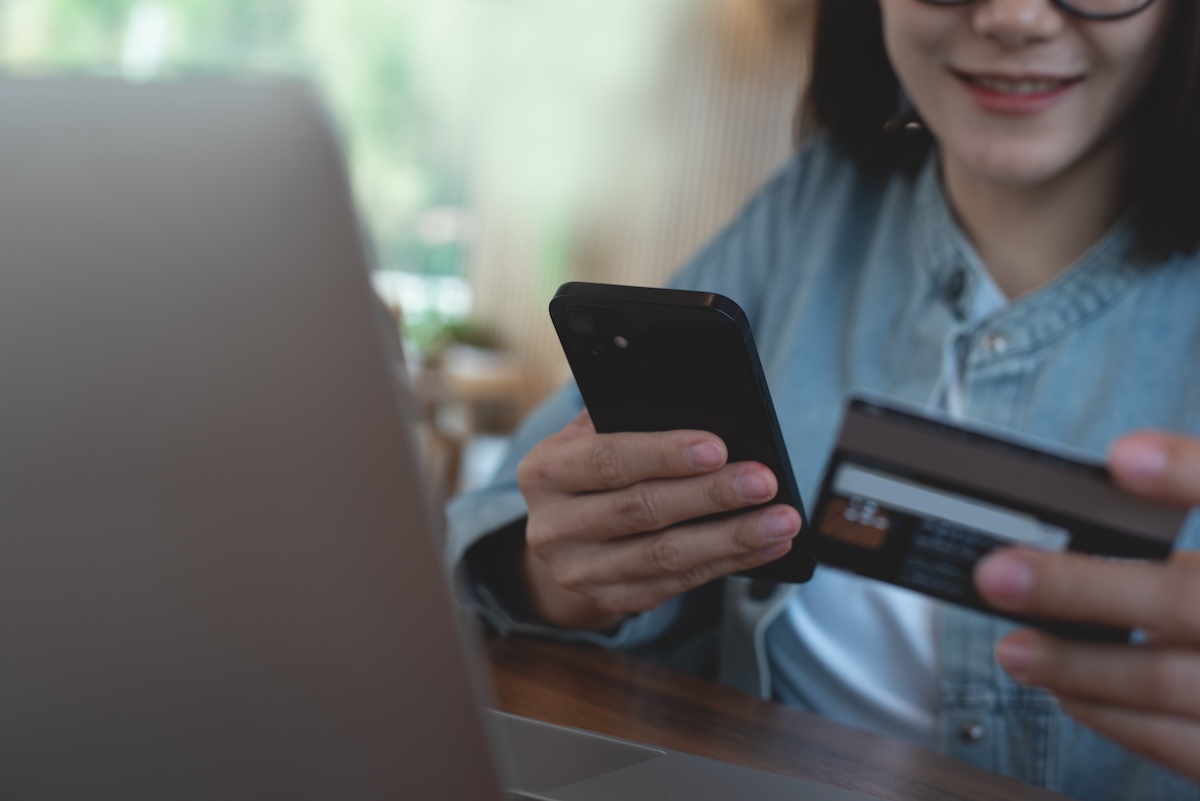 Smiling young asian woman using mobile phone and credit card for mobile banking, digital payment via mobile app. Happy user using smartphone for online shopping and internet payment, financial technology