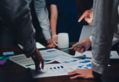 Millennial Asia businessmen and businesswomen meeting brainstorming ideas about new paperwork project colleagues working together planning success strategy enjoy teamwork in small modern night office.